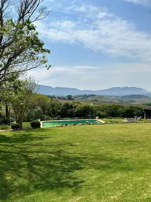 a grassy field with a swimming pool in the distance at Blossom Cottage, Elgin Grabouw in Grabouw