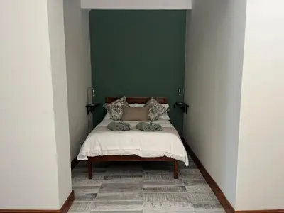 a bedroom with a bed with a green wall at Te Môi in Paarl