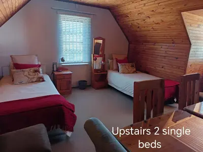 a attic bedroom with two beds and a chair at Hes Se Gang family home,in Vermont in Hermanus