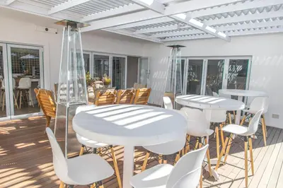 a patio with white tables and white chairs at theLAB Franschhoek in Franschhoek