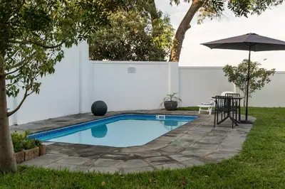 a swimming pool in a yard with an umbrella at AnnaNella Boutique Hotel in Durbanville