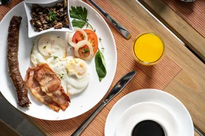 a plate of breakfast food with eggs bacon and meat at AnnaNella Boutique Hotel in Durbanville