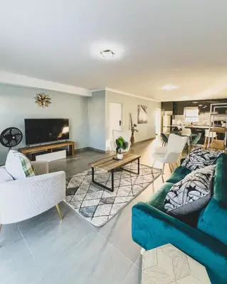 a living room with a blue couch and a table at Goodness Century Apartment in Cape Town