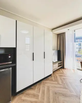 a kitchen with white cabinets and wooden floors at Grace On Park by Dajosha in Cape Town