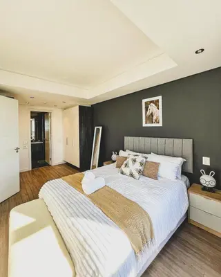 a bedroom with a large bed with a gray wall at Shalom on Matrix by Dajosha in Cape Town