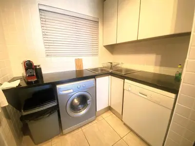 a kitchen with a washing machine and a sink at Goldwater 7 in Gordonʼs Bay