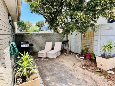 two white chairs sitting in a yard next to a brick wall at Dolce in Cape Town