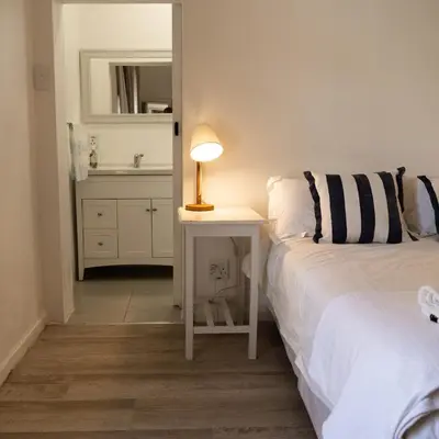 a bedroom with a bed and a table with a lamp at Mountainside Beach House in Hermanus