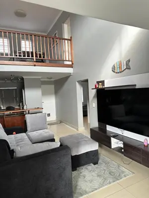 a living room with a couch and a flat screen tv at YA Eagle Wings Self Catering Shared Single Room Lodge A in Cape Town