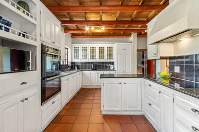 a kitchen with white cabinets and black counter tops at Farmhouse in Cape Town
