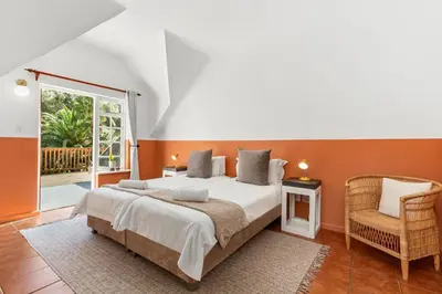 a bedroom with a large bed and a chair at Farmhouse in Cape Town