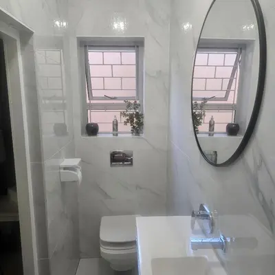 a white bathroom with a sink and a mirror at Mimi's in Plattekloof