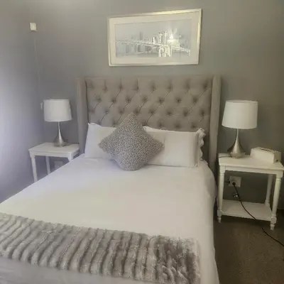 a bedroom with a large white bed with two lamps at Mimi's in Plattekloof
