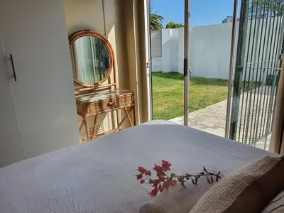 a bedroom with a bed and a mirror and a window at Casa La Mer Guesthouse in Strand
