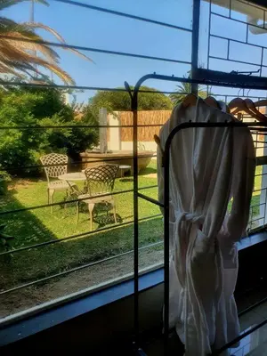a bed in a window with a view of a yard at Casa La Mer Guesthouse in Strand