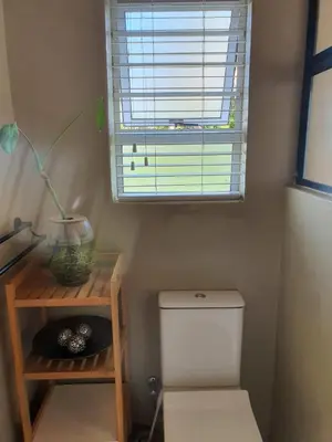 a small bathroom with a toilet and a window at Casa La Mer Guesthouse in Strand