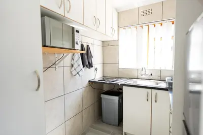 a small kitchen with white cabinets and a sink at Mystical Serenity in Durbanville
