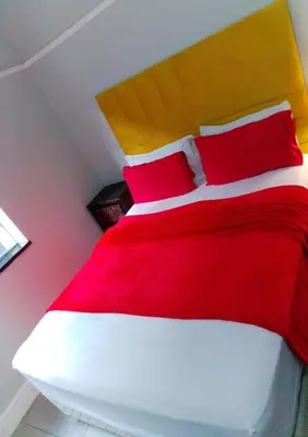 a bedroom with a red and white bed with red pillows at Neo & Ruks rooms parow 2 in Avondale