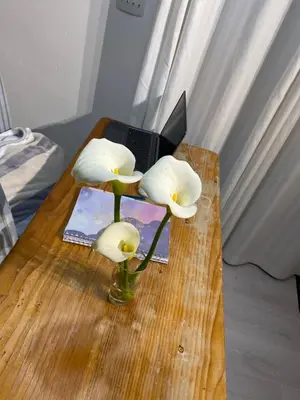 a table with a vase with white flowers and a laptop at The eden in Faure