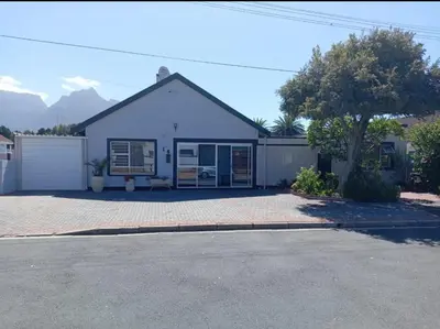 a white house with a tree and a driveway at Miches House in Cape Town