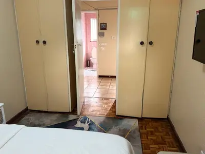a room with a bed and a hallway with cabinets at Miches House in Cape Town