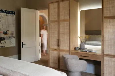 a woman is standing in a bedroom with a bed at Pink Door Franschhoek by The Oyster Collection in Franschhoek
