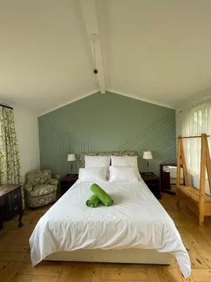 a bedroom with a bed with two green pillows on it at Green Cottage, Elgin Grabouw in Grabouw