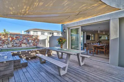 a wooden deck with a picnic table and a dining room at Somer Sout in Voelklip, Hermanus in Hermanus