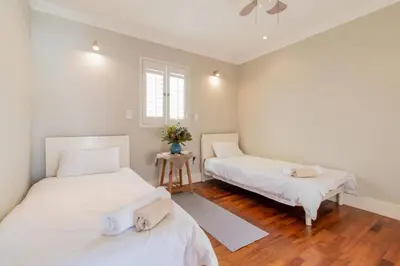 two beds in a room with white walls and wooden floors at Somer Sout in Voelklip, Hermanus in Hermanus