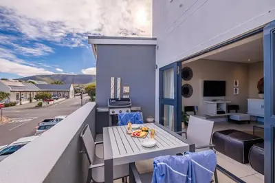a patio with a table and chairs on a balcony at Hermanus Marine Square spacious 1 bedroom- central & close to sea in Hermanus