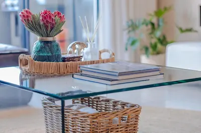 a glass table with books and a basket of flowers at Hermanus Marine Square spacious 1 bedroom- central & close to sea in Hermanus