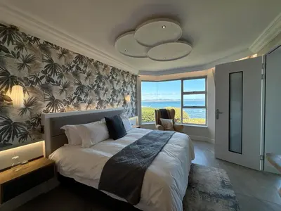 a bedroom with a large bed and a large window at Bayview 107 in Hermanus