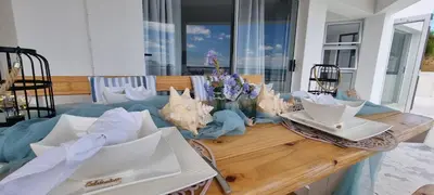 a wooden table with plates and flowers on it at Coral Vistas Self Catering Apartments in Gordonʼs Bay
