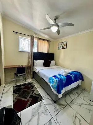 a bedroom with a bed and a ceiling fan at Kitty Guest House in Bellville