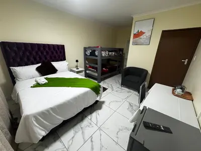 a bedroom with a bed with a green blanket at Kitty Guest House in Bellville