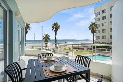 a table and chairs on a balcony with a view of the ocean at 14 Cap dAzur by Host Agents in Cape Town