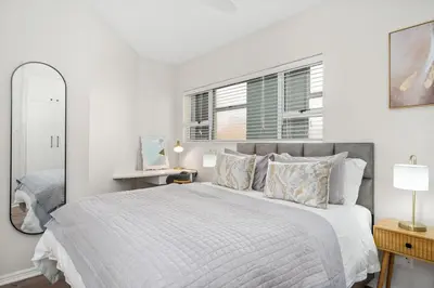 a white bedroom with a large bed and a mirror at 14 Cap dAzur by Host Agents in Cape Town