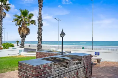 a barbecue grill with the beach in the background at 14 Cap dAzur by Host Agents in Cape Town