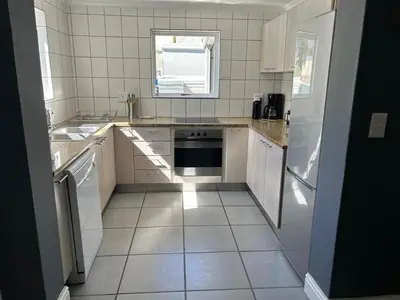 a white kitchen with a sink and a dishwasher at Lemon Tree Cottage a Charming 3 Bedroom Self-catering house in Franschhoek