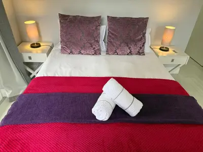a bed with two white towels on it with two lamps at Lemon Tree Cottage a Charming 3 Bedroom Self-catering house in Franschhoek