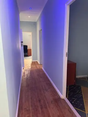 an empty hallway with purple walls and wooden floors at Comfort Guest House in Tiervlei