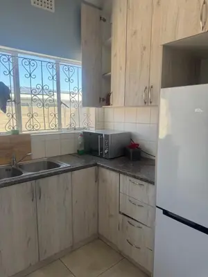 a kitchen with wooden cabinets and a white refrigerator at Comfort Guest House in Tiervlei