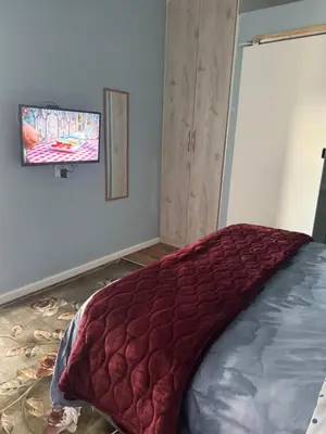 a bedroom with a bed with a red blanket on it at Comfort Guest House in Tiervlei