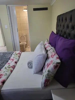 a bed with pillows on it in a room at Comfort Guest House in Tiervlei