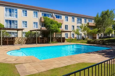 a swimming pool in front of a building at Pinelands Apartment in Cape Town