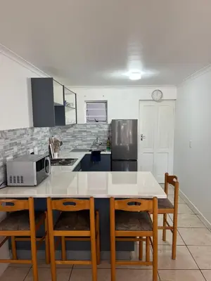 a kitchen with a table with chairs and a microwave at Pinelands Apartment in Cape Town