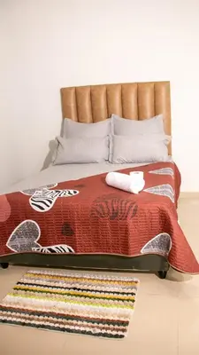 a bed with a red comforter and a rug at Gift Guest house 2 in Cravenby