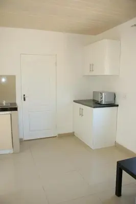 an empty kitchen with white cabinets and a microwave at Gift Guest house 2 in Cravenby