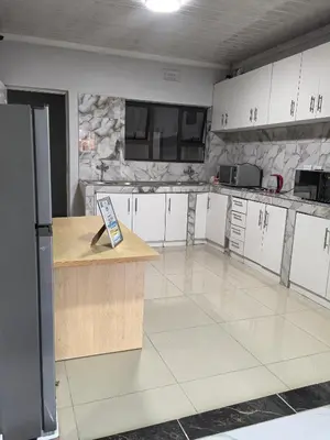a large kitchen with white cabinets and a counter at Gift Guest house 1 in Cravenby
