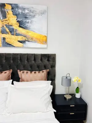 a bedroom with a bed and a painting on the wall at Cottage in Cape Town
